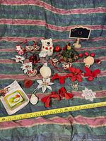 Front angled view of assorted Christmas decorations arranged on multicolored fabric with measuring tape at bottom.