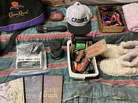 Photo showing white fleece slippers, Crooks hat, Crown Royal bag, box with assorted items including pet collars, and wooden plaques