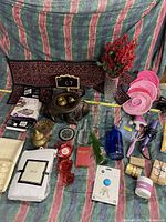 Full view of assorted household items including decorative pieces, candles, soaps, and bottles arranged on patterned textile background.