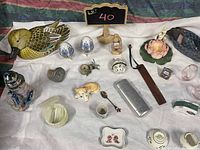Wide shot of the lot showing all items arranged on cloth including wooden duck, ceramics, decorative eggs, figurines, and other collectibles.