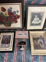 Image shows five framed pieces including floral embroidery, vintage baby photo, group photo, red brick building art, and small pink frame artwork.
