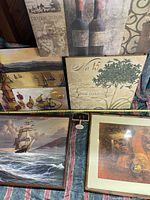 Overview image showing the majority of the art framed prints and paintings leaning on a couch and floor against a dark background