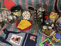 Photo of entire kitchen lot showing spice rack, crockpot, mixing bowl, child’s chef hat, linens, and food items.