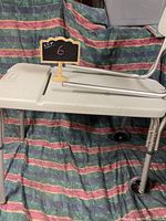 Full side view of the white plastic and metal frame Lumex bathroom utility device showing length, wheels, and side rails.