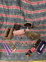 Photo showing all items in the lot including black horse head statue, quartz scepter in pink case, metal hand fan, candles and various pins and brooches.