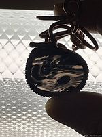 Close-up of a pendant featuring Turritella Agate stone with distinctive shell patterns and copper wire wrapping.