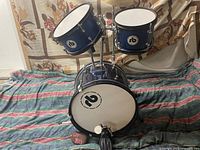 Full view of the 4-piece youth drum set displayed on a striped cloth backing with mounted toms, snare drum, and bass drum