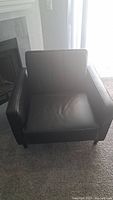 Front view of black faux leather loveseat chair showing cushioned seat and straight armrests.