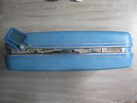 Top view of blue hard shell Samsonite suitcase showing luggage shape, handle, and blue color