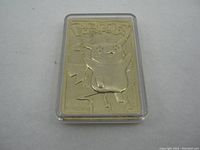 Front view of gold-tone metal Pikachu card in protective case