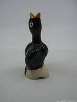 Front angled view of the black bird ceramic pie funnel showing details of the wings, eye, and yellow beak.
