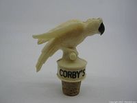 White parrot cork stopper pourer with 'CORBY'S' label from an angled view showing details of the bird and cork base.