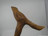 Detailed side view of bird-shaped cane handle showing carved feathers and beak with black eyes.