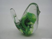 Front and left side view of the Kerry Glass hand blown bird paperweight showing the clear glass body and green inner swirl design.