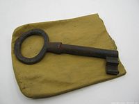 Overall image of the vintage skeleton key resting on a yellow cloth, showing the round bow and length of the key.