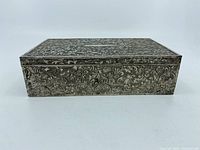 Side view of rectangular metal box showing uniform engraved floral pattern