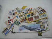 Spread of various postage stamps, some on paper remnants, displaying a wide range of colors and designs including a large $10 Canadian whale stamp.