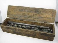 Open wooden box showing metal stocks and dies tools inside.