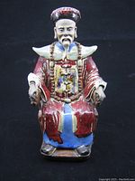 Front view of the Chinese clay figure showing detailed facial features, clothing, and seated pose.