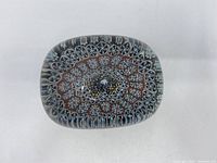 Top view of a rectangular glass paperweight with colorful millefiori floral pattern inside