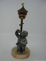 Full view of oil lamp with hobo figurine drinking from a bottle, mounted on marble base with tall oil reservoir and wick at top
