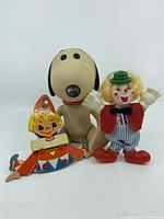 Front view of the three vintage toys - Snoopy doll, wooden clown toy, plastic clown doll