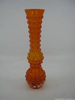 Full front view of the tall orange hobnail glass vase showing the textured pattern and overall shape.