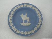 Top view of blue Wedgwood commemorative dish with white relief mounted RCMP officer and maple leaf border.