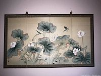 Frontal image of the folding Asian screen showing two painted panels with lotus flowers and birds, dark bordered frame, and two hanging hooks at top.