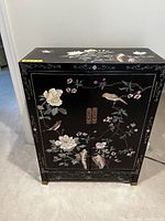Front view of closed cabinet showing floral and bird painting