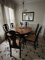 Zoomed out view of oval pedestal dining table with six chairs in dining room