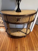 Foyer table from front showing the floral painted top, drawer front, and lower shelf