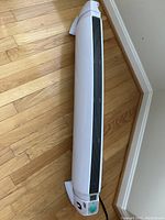 White floor heater with tall, slim design and control panel at one end