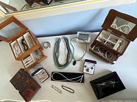 Overhead view showing four jewelry boxes, assorted necklaces, bracelets, earrings, brooch and digital clock