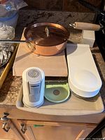 Overview of miscellaneous kitchen items including copper saucepan, digital thermometer, plastic container, soap holder, and small utensil.