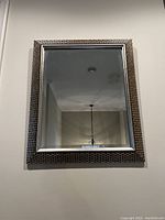 Rectangular modern silver-framed wall hanging mirror showing clear reflective surface and textured wide frame detail.