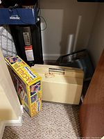 View showing Millville heater, McCalls weaving loom box, vintage Singer sewing machine in beige hard case, and blue foot spa machine on floor.