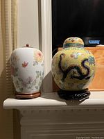 Pair of Chinese ginger jars side by side. One white with floral design, one yellow with dragon and butterfly motifs.