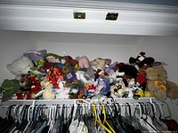 Wide view of shelf filled with multiple stuffed animals piled together showing variety and quantity