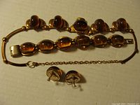 Photo of copper tone necklace and bracelet, amber-like stones, and tarnished sterling clip-on earrings.