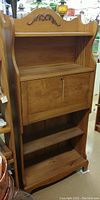 Front view of solid maple drop front desk with key hanging, showing closed drop front and open shelves.
