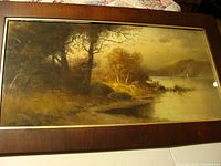 Full view of the framed antique landscape print showing trees, water, and hills with muted colors.