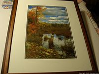 Full view of framed lithograph print showing autumn landscape with pond and reflective water.