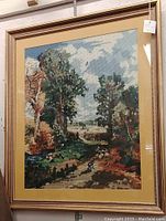Full view of the large framed needlepoint landscape showing the entire frame, mat, and needlepoint artwork depicting trees, sky, and a path.