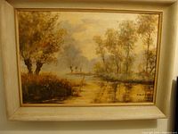Framed landscape oil painting showing river and trees with autumn colors