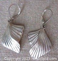 Front and angled view of silver drop earrings showing grooved detailed design and lever back