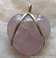 Close-up of front of rose quartz heart pendant showing sterling silver wire wrapping and detailing.