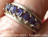 Close-up of the band ring showing seven square-shaped blue stones, prong set.