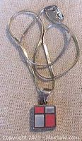 Full view of the sterling silver herringbone chain with attached square pendant.