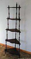 Full view of vintage walnut finish corner whatnot, showing five corner shelves supported by turned spindle posts and finials.